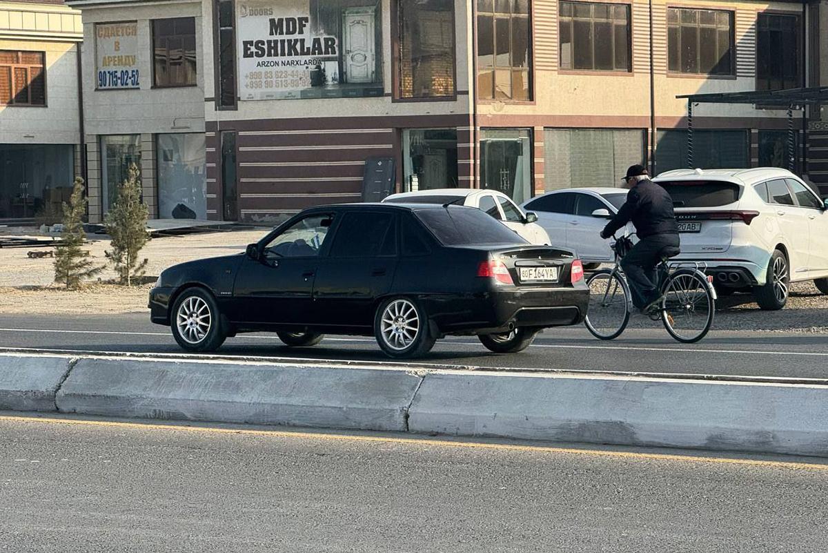 Автомобиль и велосипедист на дороге Узбекистан